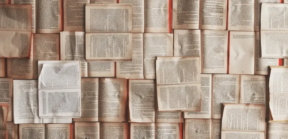 Dozens of open book pages laid edge to edge, filling the frame with printed text.