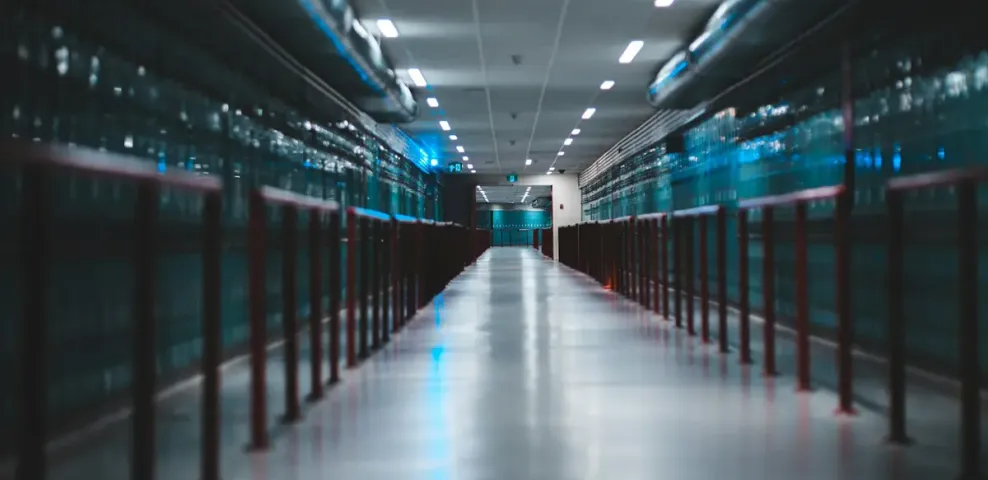 A long aisle running between two rows of blue lit server cabinets in a data center.