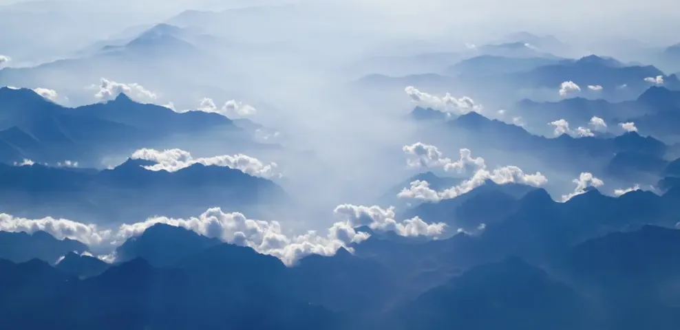 Blue mountain ridges receding into the distance through separated layers of cloud.