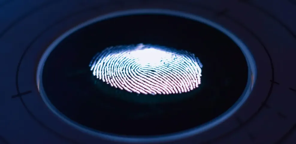 A glowing fingerprint on the surface of a dark circular biometric scanner.