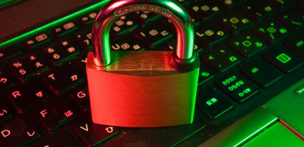 A metal padlock closed on top of an illuminated computer keyboard.
